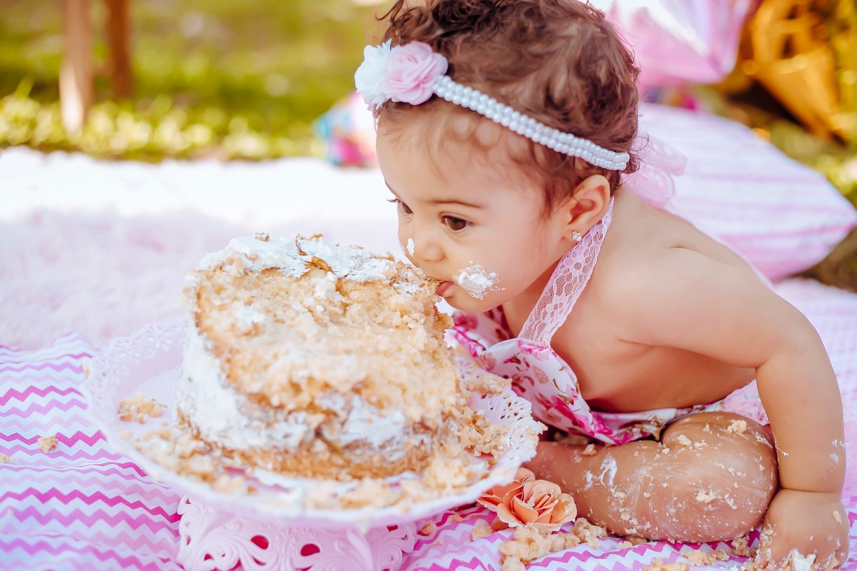 Real photograph of a child enjoying a birthday cake outdoors